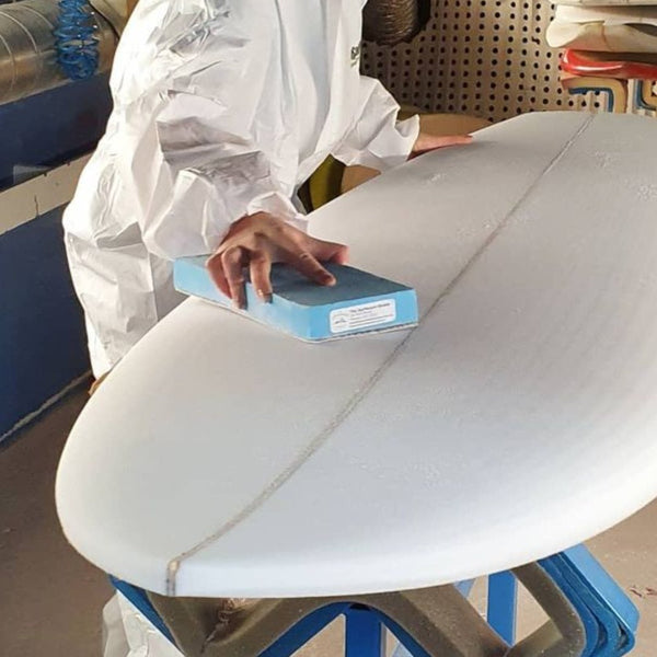 Sanding down the foam surfboard blank pre glassing.