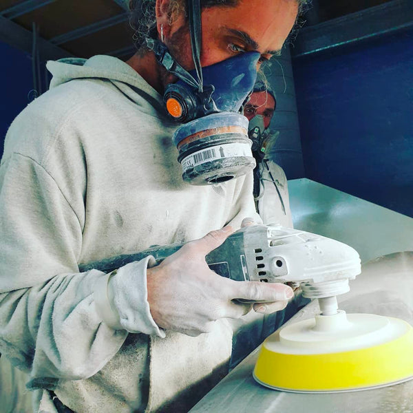 The Surfboard Studio - Sanding Pads buffing a surfboard with the pad attachment on a grinder.